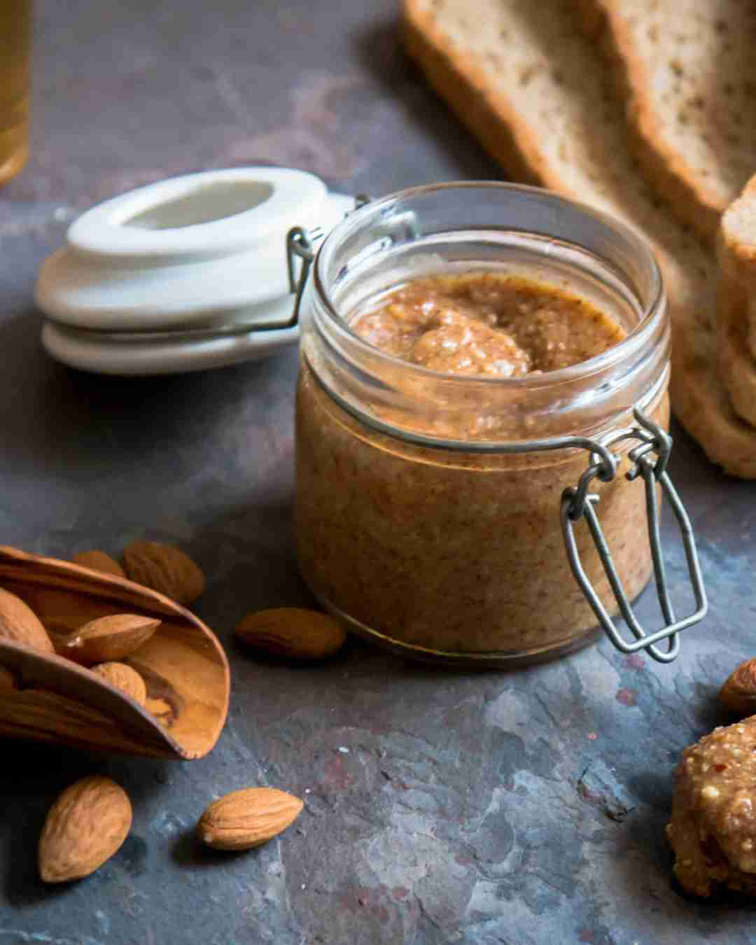 Kozarec tradicionalnega maroškega namaza amlou iz mandljev, arganovega olja in medu, obdan s celimi mandlji in rezinami kruha – simbol bogate prehranske vrednosti in kulinarične dediščine Maroka.