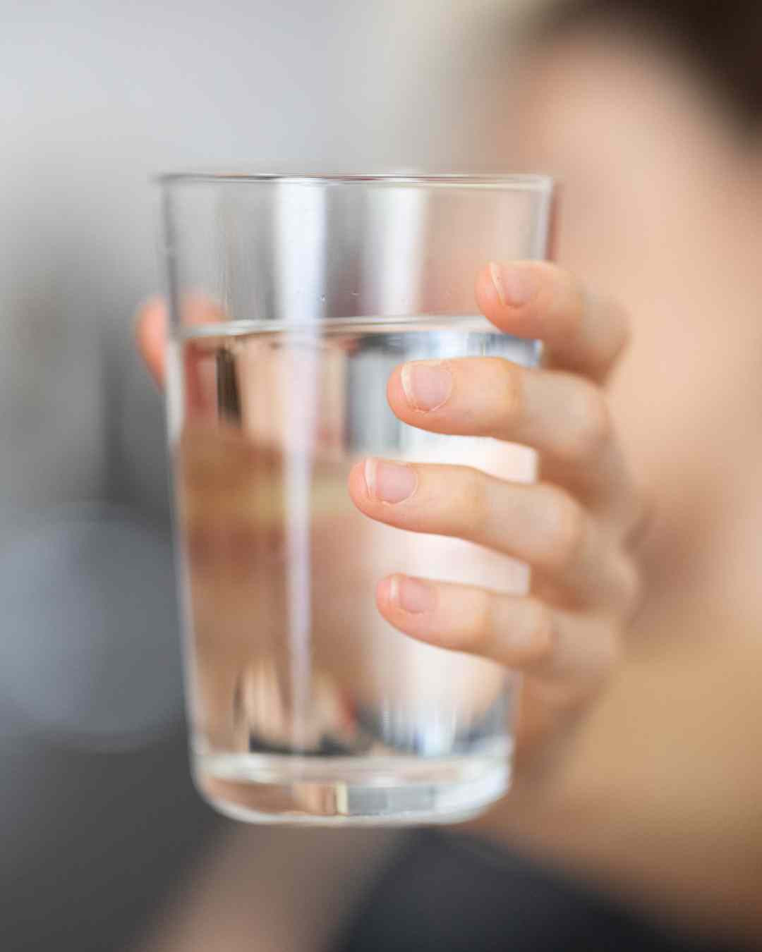 Roka drži kozarec vode – uporaba Bachovih kapljic, razredčenih v vodi.