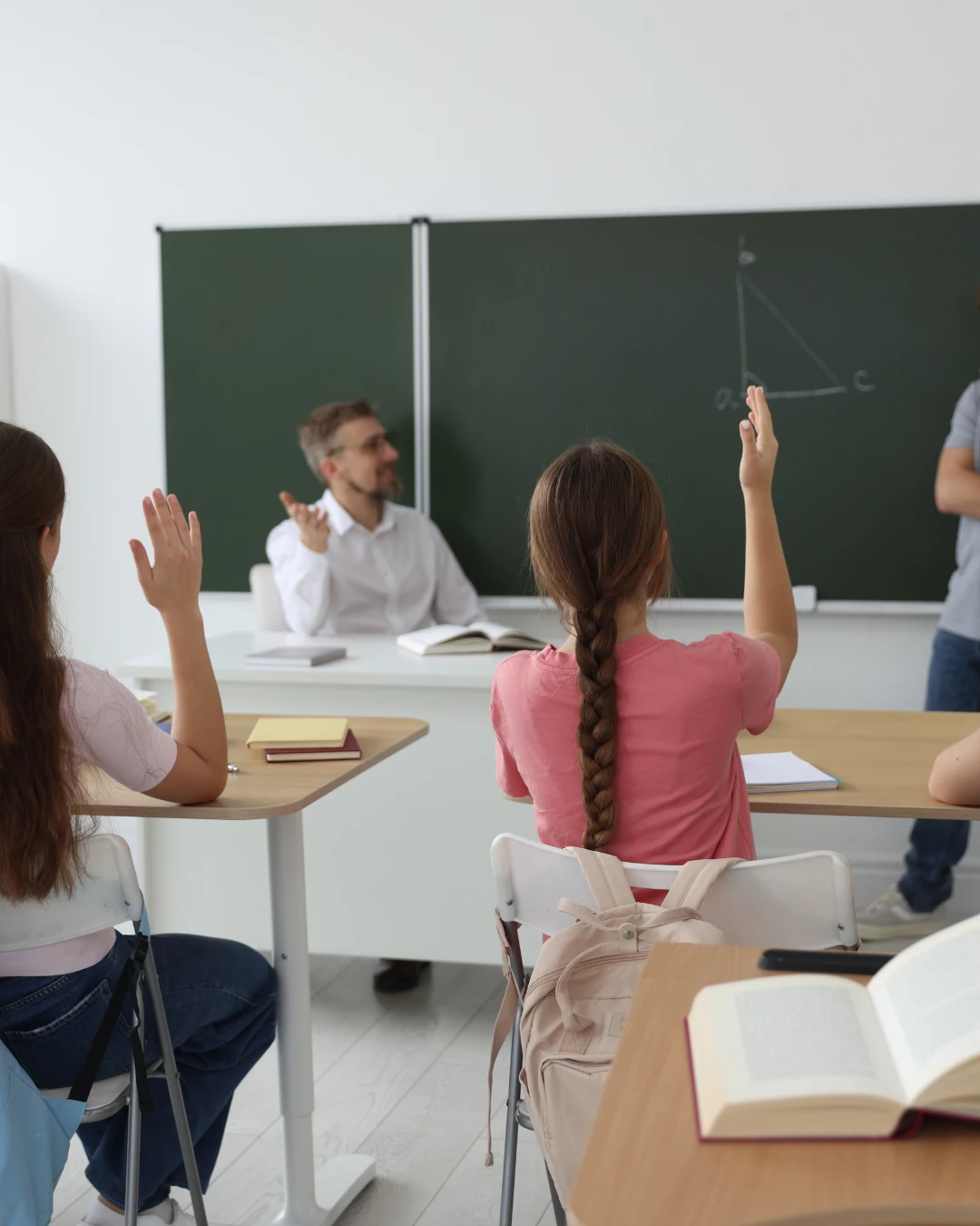 Otroci pri pouku z dvignjeno roko – učenje, zbranost in koncentracija v šolskem okolju.