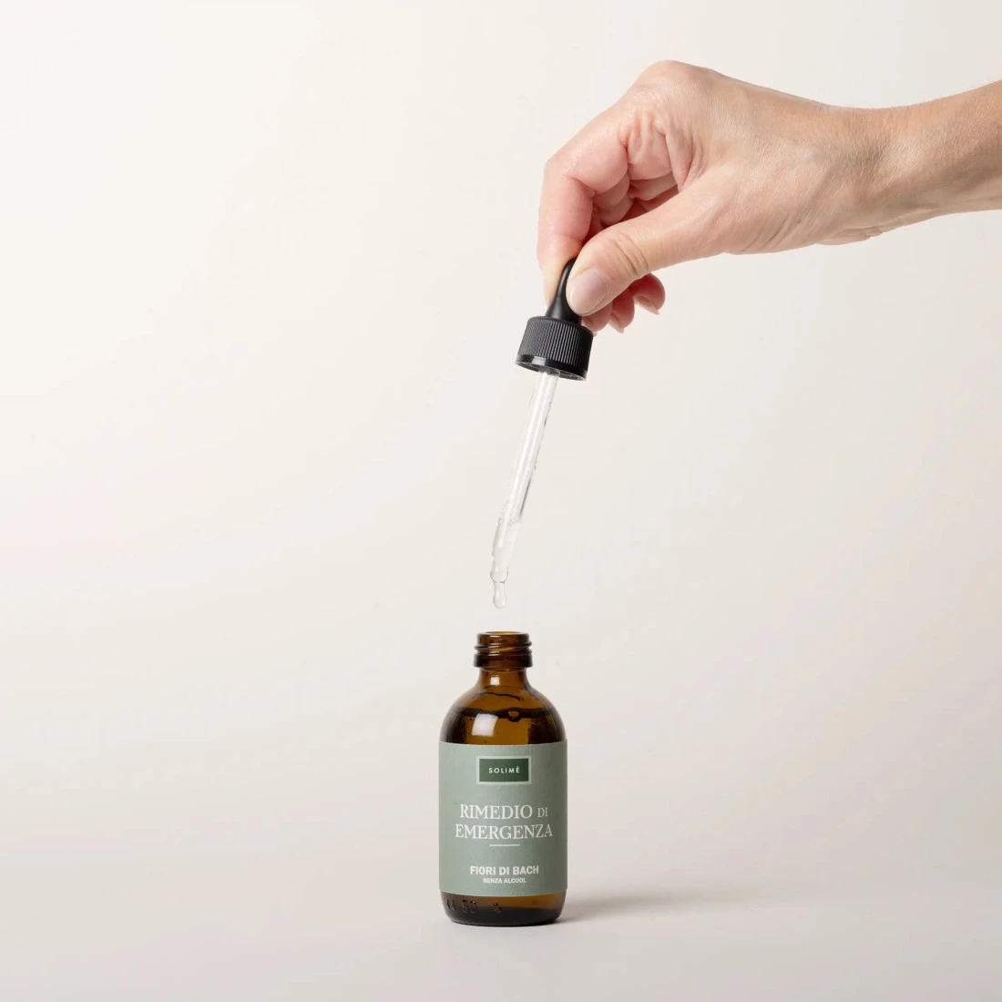 Roka drži pipeto nad stekleničko Bachovih cvetnih kapljic Solimè »Rimedio di emergenza« brez alkohola – prikaz pravilne uporabe naravne esence.