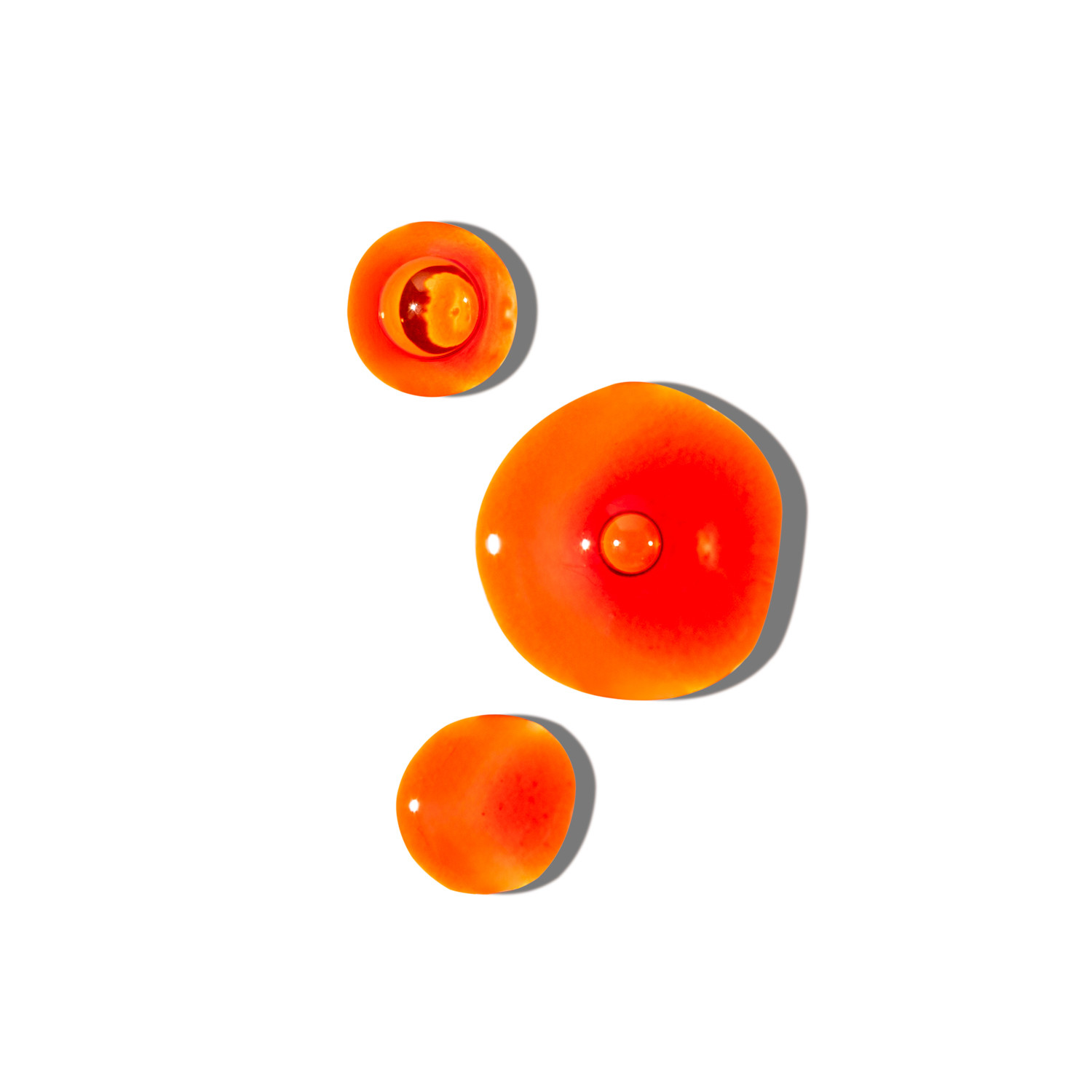 Rdečkasto-oranžne kapljice olja na beli podlagi – simbol naravne zaščite, hranilnih maščob in zdravja možganov