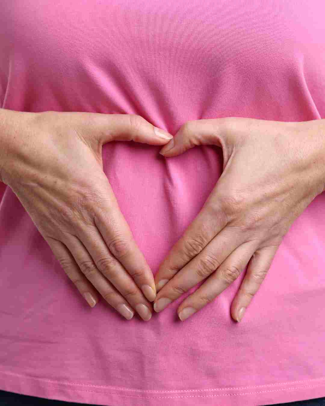 Roke v obliki srca na trebuhu kot simbol zdravja prebave in črevesja.