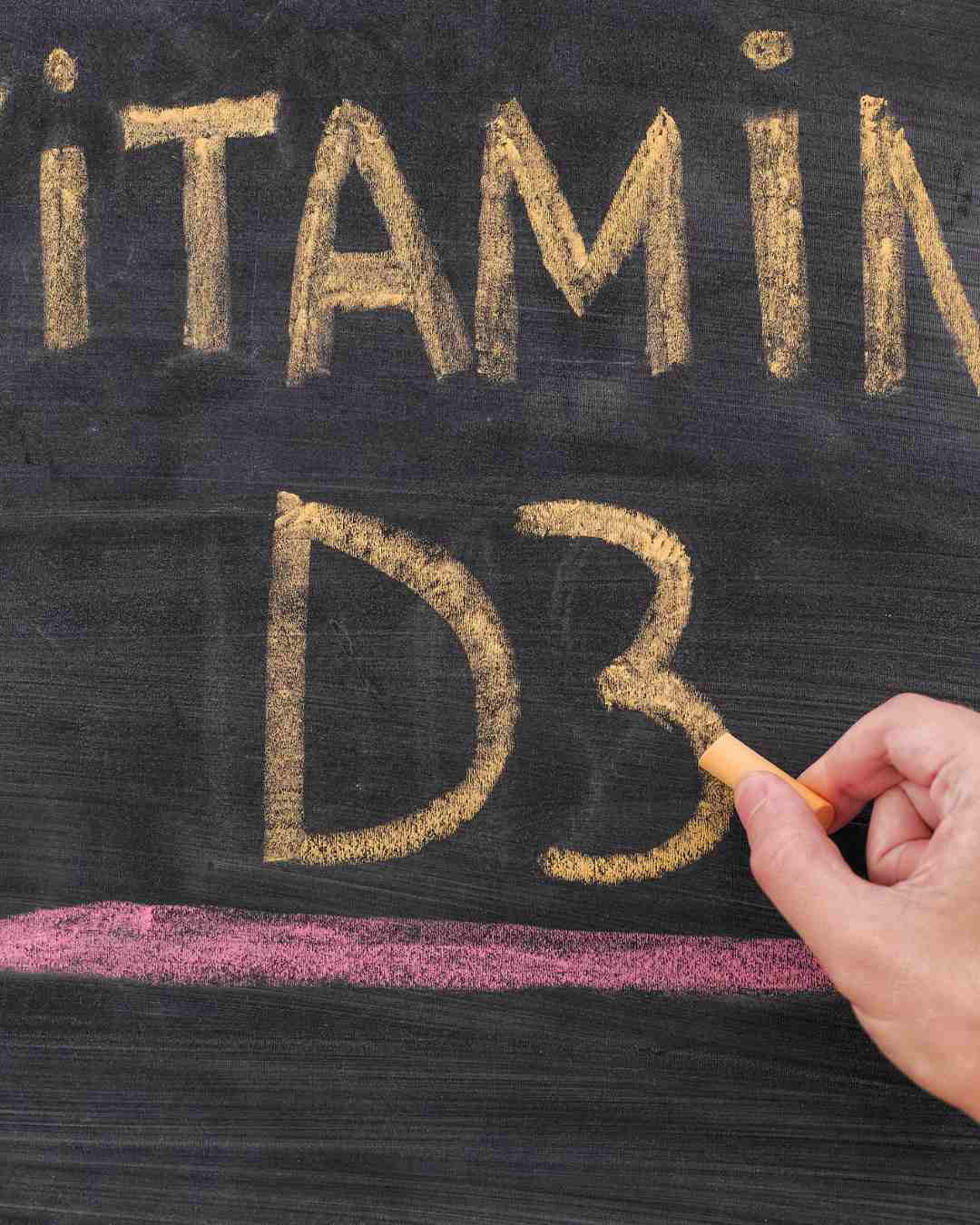Ročno napisan napis »Vitamin D3« s kredo na črni tabli – poudarja pomembnost vitamina D3 za zdravje kosti, mišic in imunski sistem.